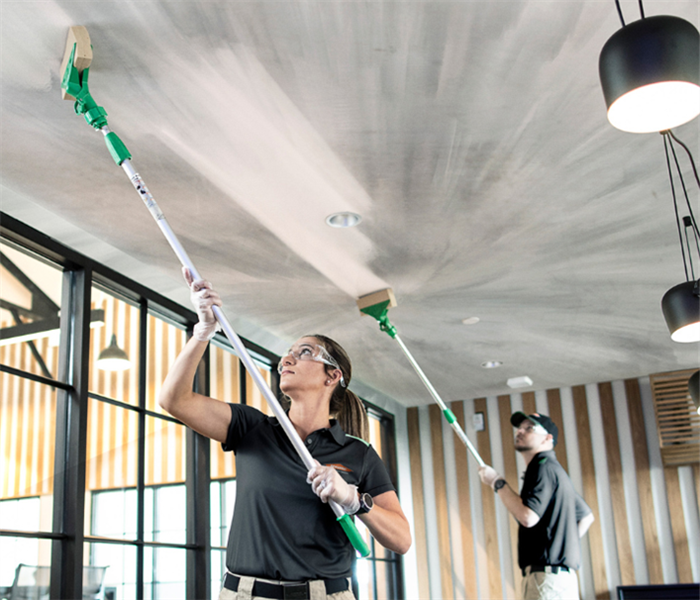 SERVPRO employees cleaning the ceiling with equipment. 